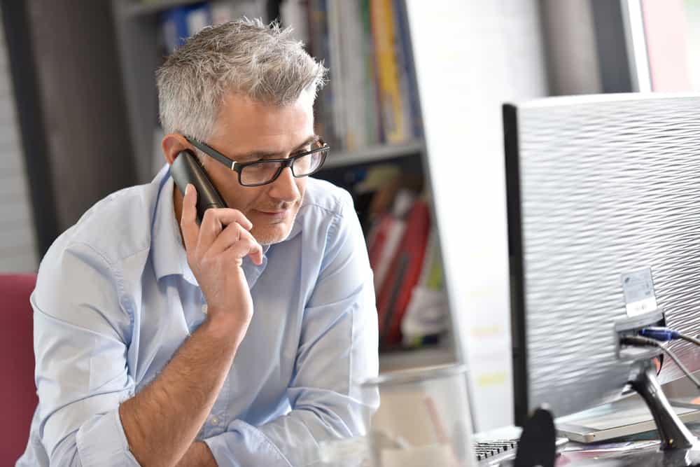 Ein Mann im Büro sitzt und telefoniert