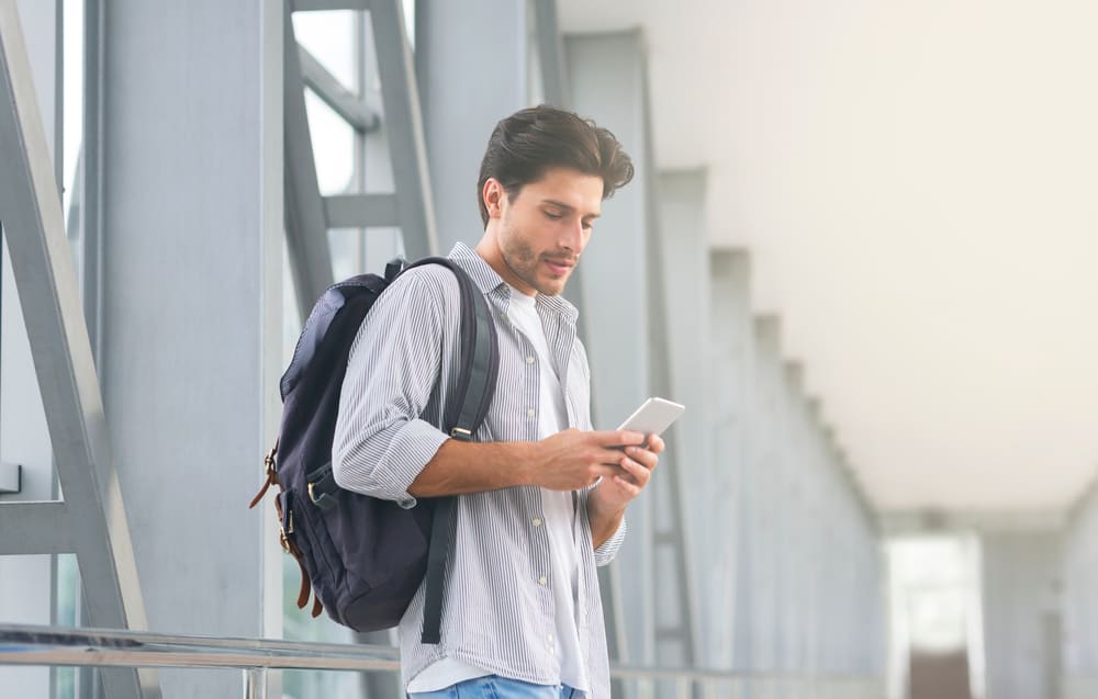 Ein Mann mit einem Rucksack schreibt eine SMS