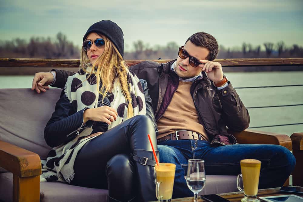 Ein Mann sieht trotzig eine attraktive Frau an, mit der er auf der Terrasse eines Cafés sitzt