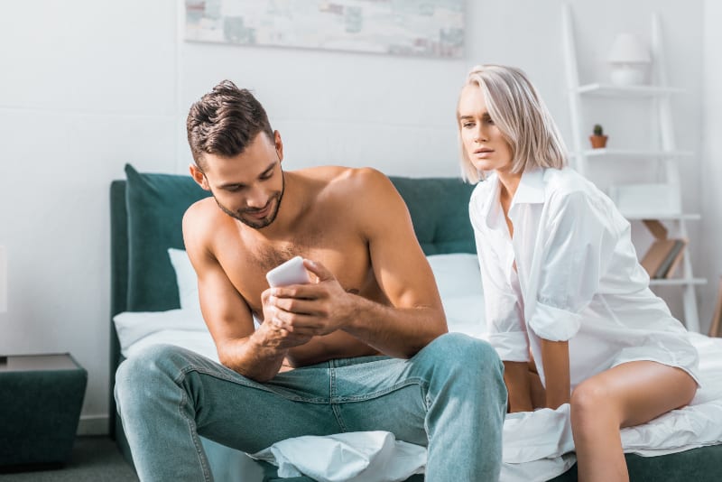 Ein Mann versteckt sein Handy vor einem Mädchen