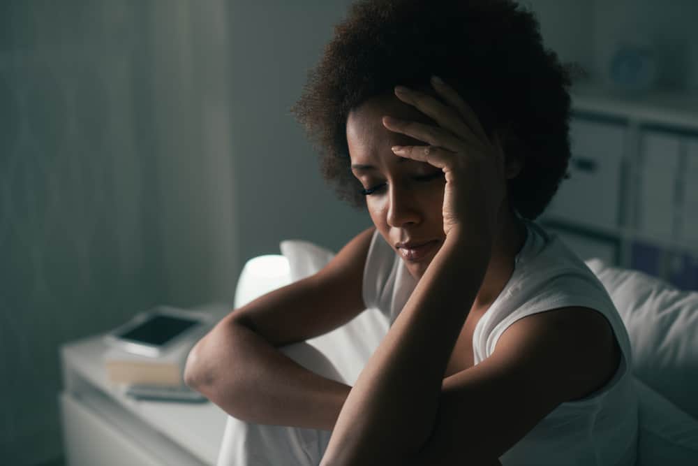 Eine depressive schwarze Frau sitzt mit geschlossenen Augen