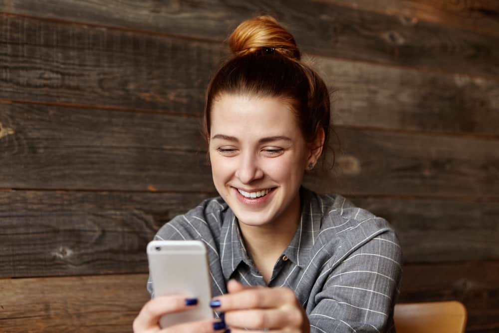 Eine glückliche Frau liest eine Nachricht auf ihrem Handy
