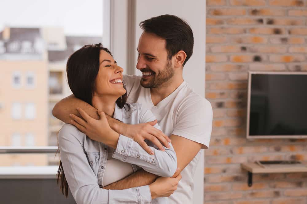 In der Wohnung steht in den Armen eines schönen lächelnden Liebespaares