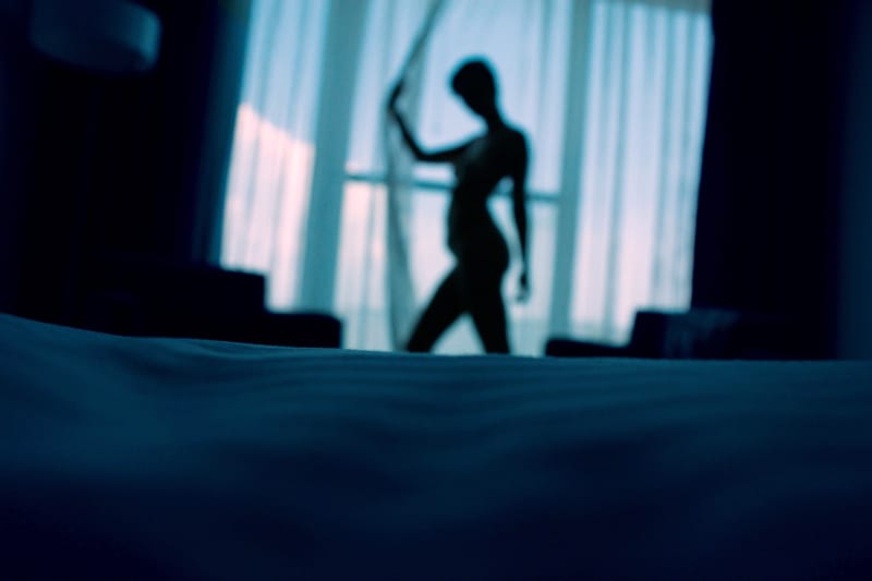 Schattenbildfoto der Frau, die neben Fenstervorhängen steht