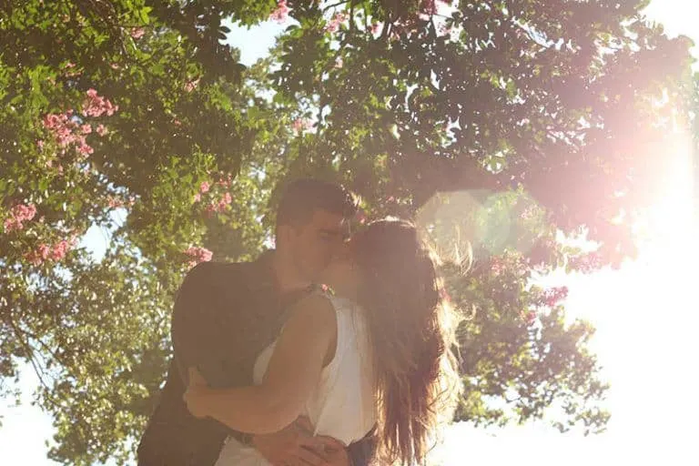 Ein junger Mann und eine junge Frau küssen sich unter einem Baum
