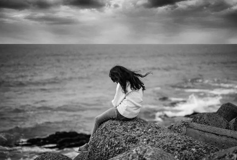 traurige Frau, die allein am Meer sitzt