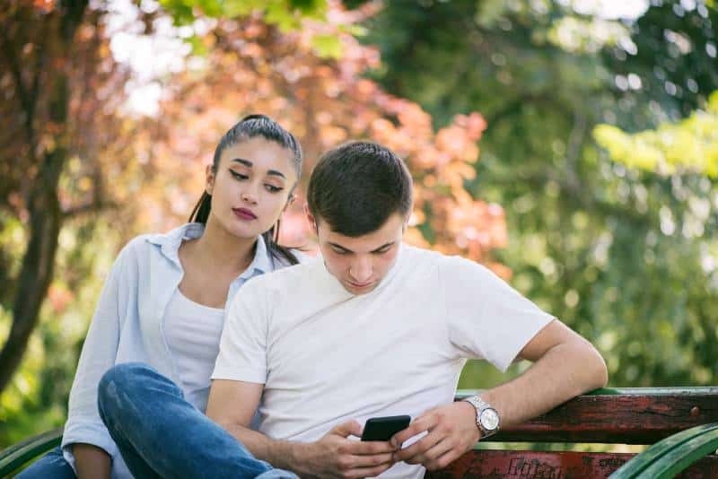 eifersüchtige Frau, die Mann Telefon ansieht