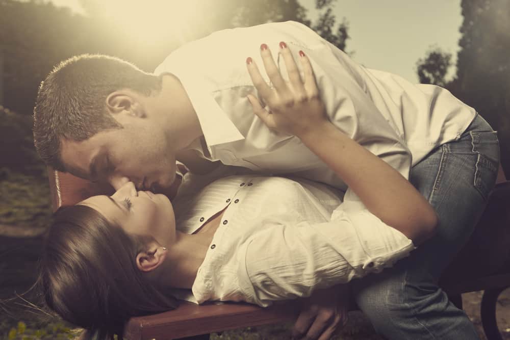 ein liebendes Paar, das sich leidenschaftlich auf einer Parkbank küsst