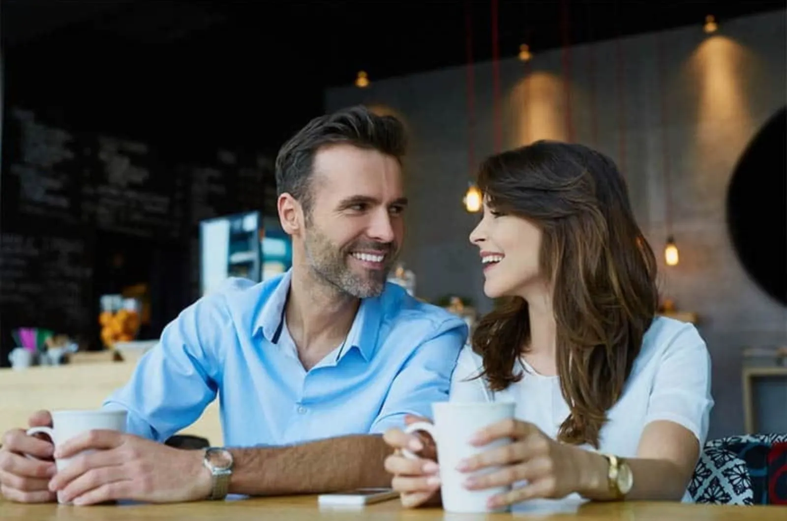 laechelnder Mann und Frau sitzen im Cafe