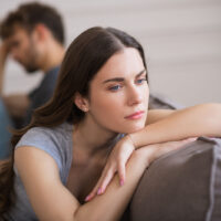 Junge Frau sitzt und sieht nach einem schlechten Gespräch mit ihrem Mann verärgert aus
