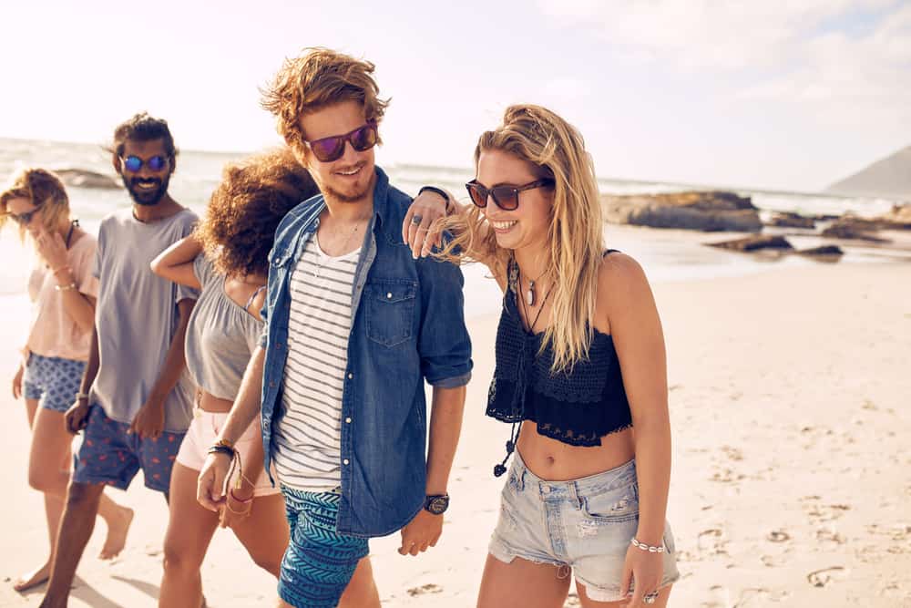 Drei Frauen und zwei Männer gehen am Strand entlang