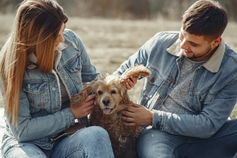 Ein Paar in Texas Jacken sitzt mit einem braunen Hund