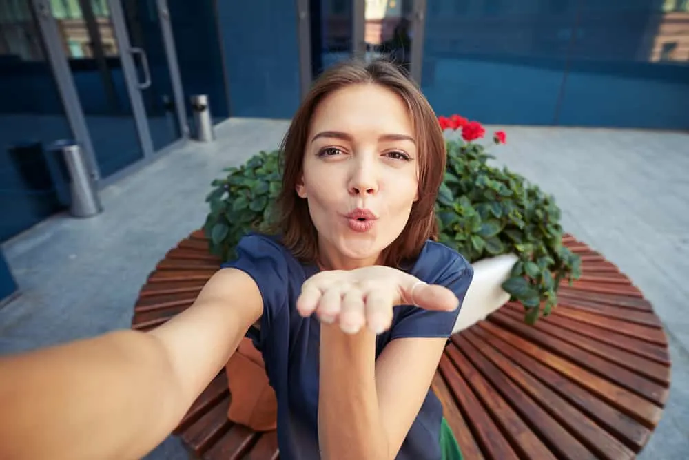 Eine Frau mit einer Kuss-Pose macht ein Selfie-Foto