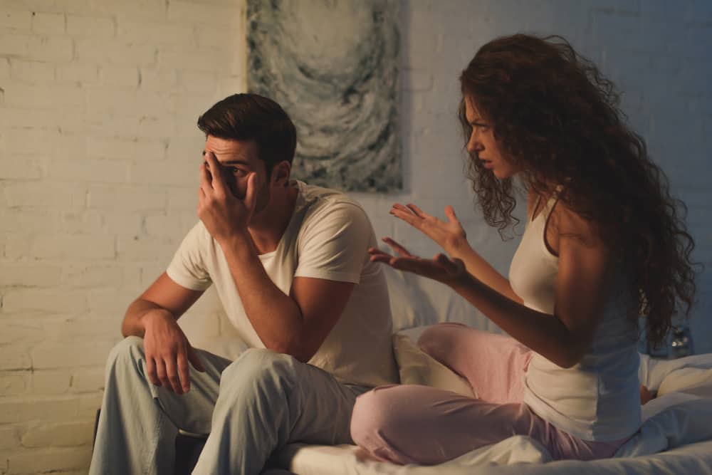 Im Schlafzimmerbett ignoriert der Mann die Frau, die ihm etwas erzählt