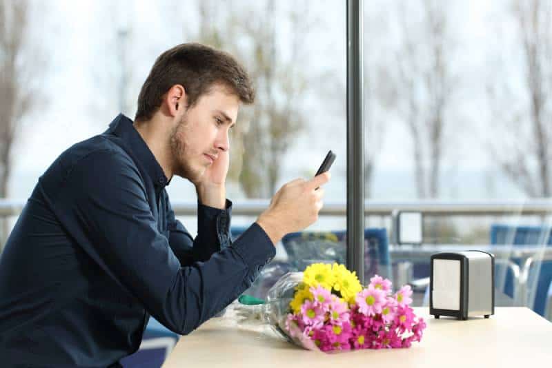 Mann, der Telefon unglücklich ansieht