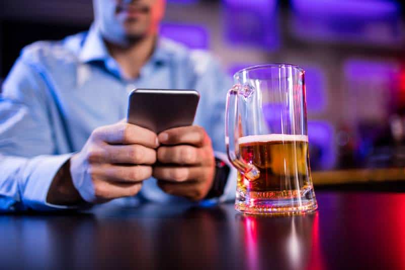 Mann mit Handy am Bartheke in der Bar