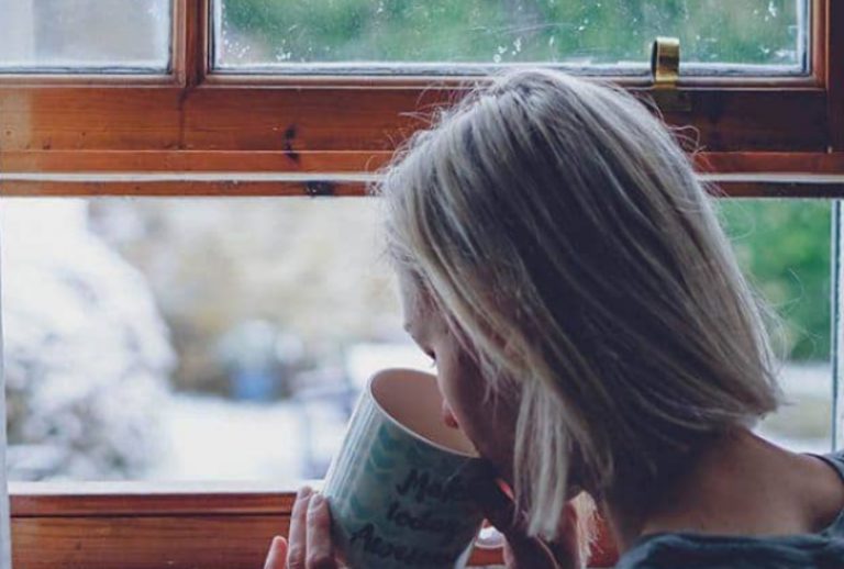ein Mädchen, das Kaffee am Fenster trinkt
