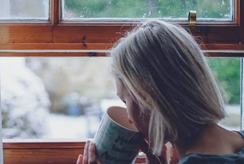 ein Mädchen, das Kaffee am Fenster trinkt