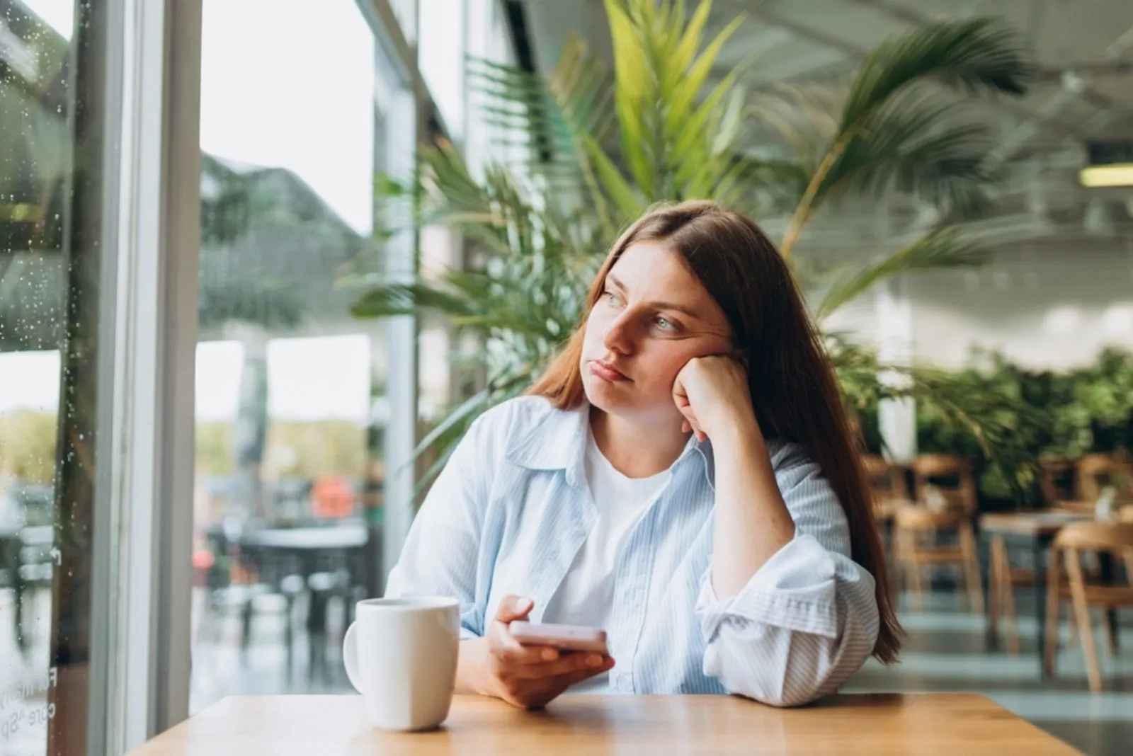 Traurige Frau mit Handy und sitzt im Cafe