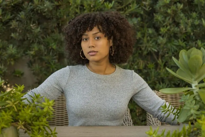 Eine attraktive schwarze Frau sitzt in einem Garten voller Grün