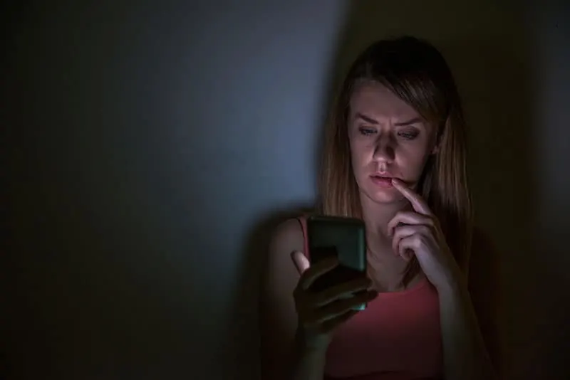 besorgte Frau, die nachts zu Hause auf ihr Telefon schaut