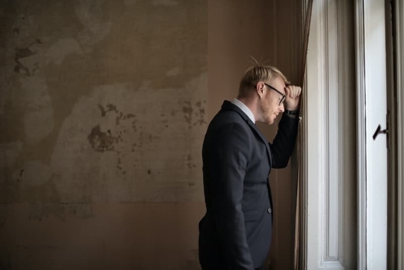 ein Geschäftsmann mit Brille am Fenster stehen