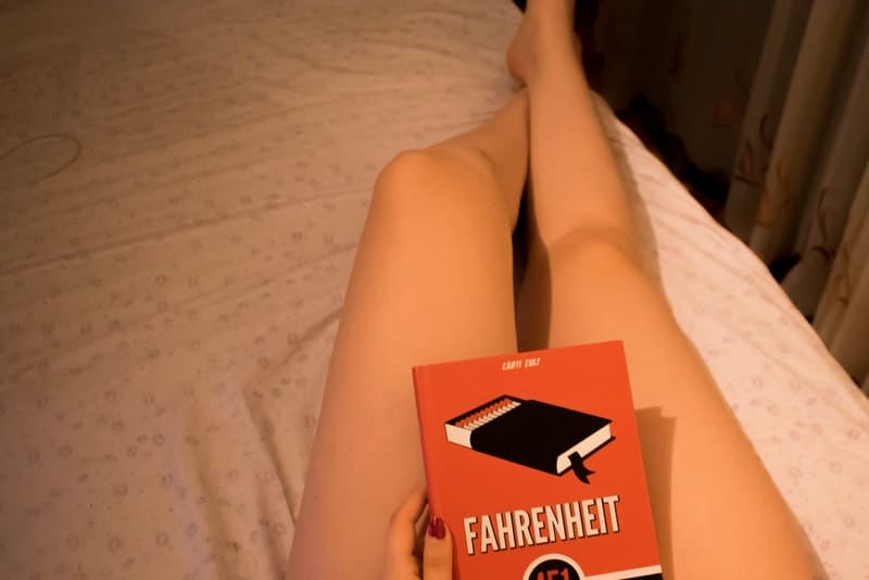 schöne weibliche Beine und ein Buch in der Hand