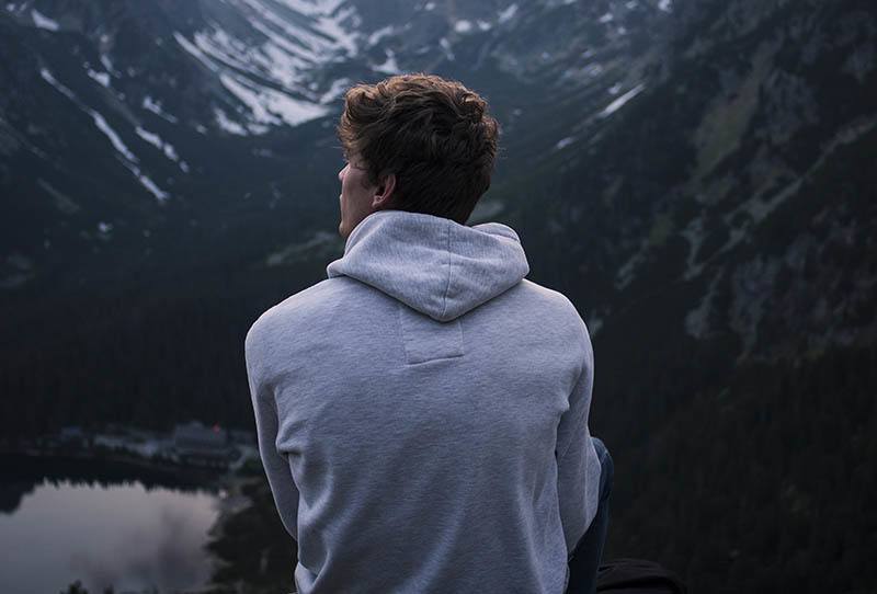 Ein Mann in einem grauen Hoodie sitzt über dem Canyon
