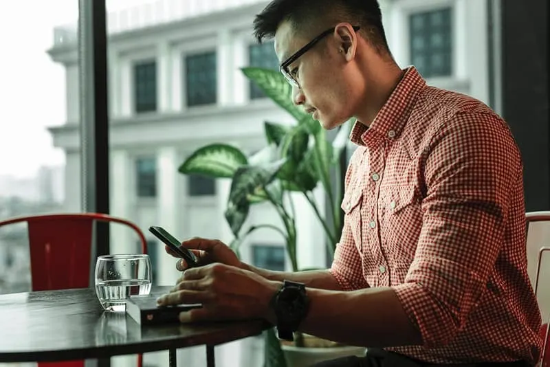 Ein Mann in einem karierten Hemd mit Brille benutzt ein Telefon