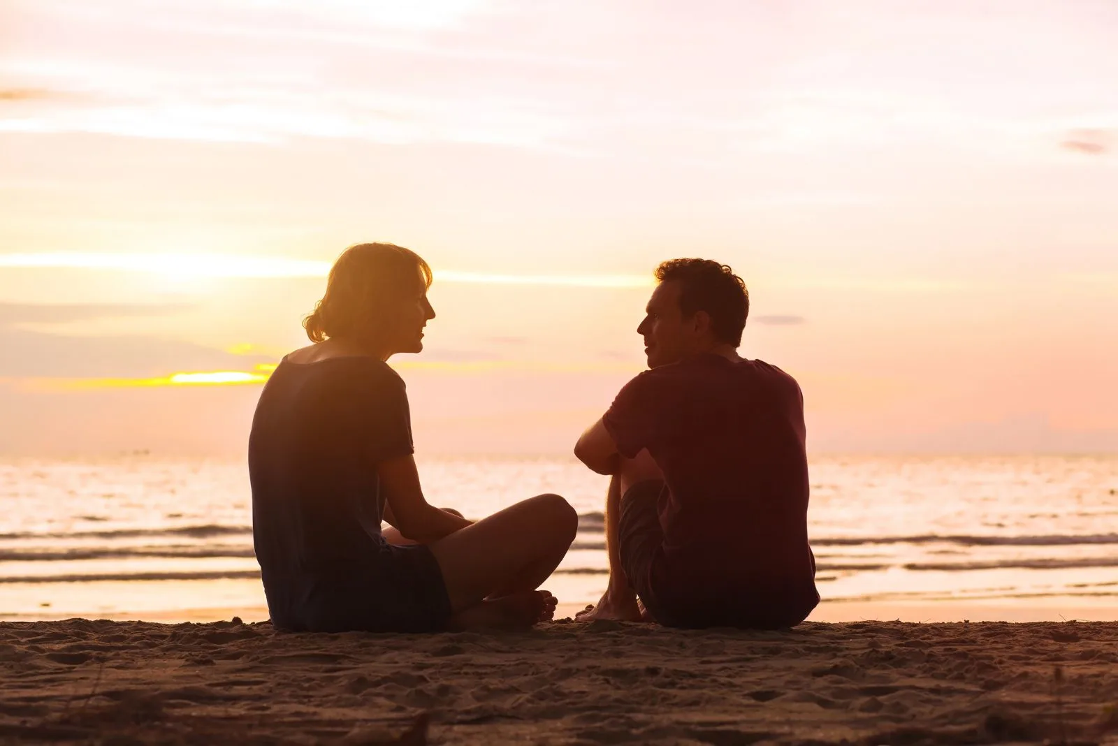 Ein Mann und eine Frau sitzen am Strand und unterhalten sich