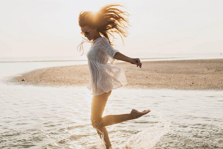 Ein junges Mädchen in einem weißen Kleid genießt das Meer