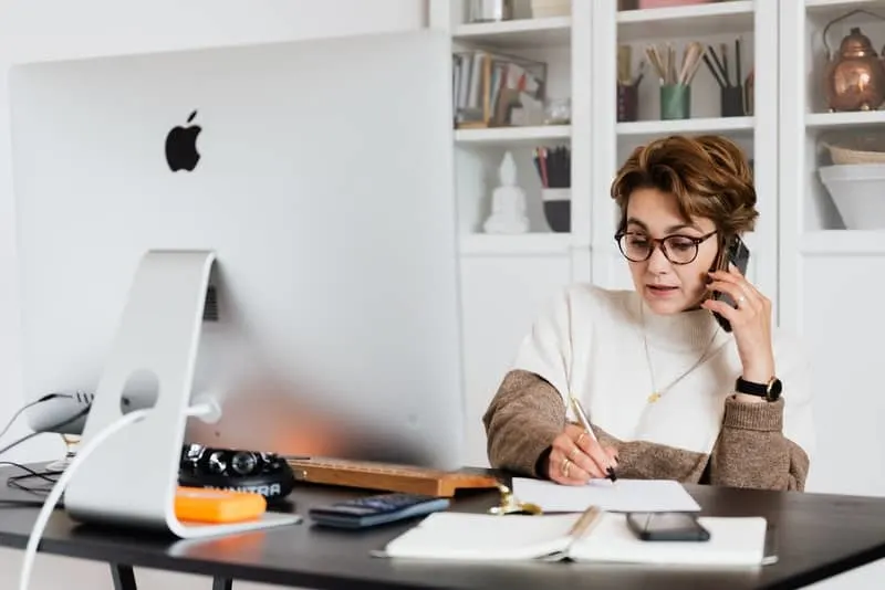 Eine Geschäftsfrau mit Brille sitzt an ihrem Schreibtisch und arbeitet