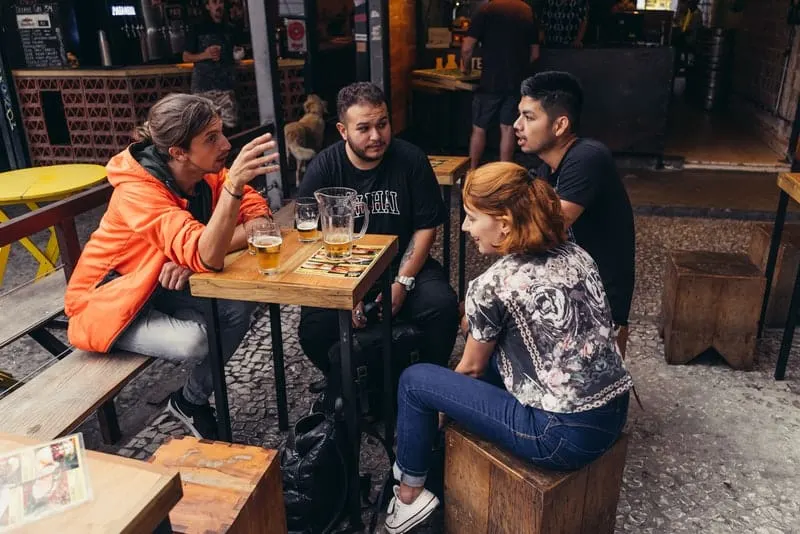 Eine Gruppe von Freunden sitzt und redet bei einem Bier