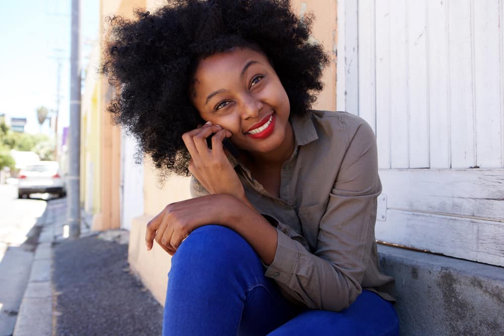 Eine attraktive lächelnde schwarze Frau sitzt auf der Treppe