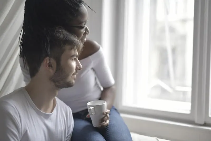 Eine junge Frau und ihr Freund sitzen und schauen aus dem Fenster