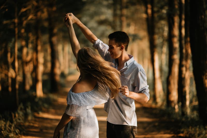 Mann mit Frau, die in der Mitte der Bäume tanzt