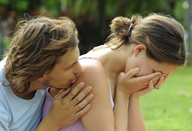 Mann tröstet seine weinende Freundin draußen