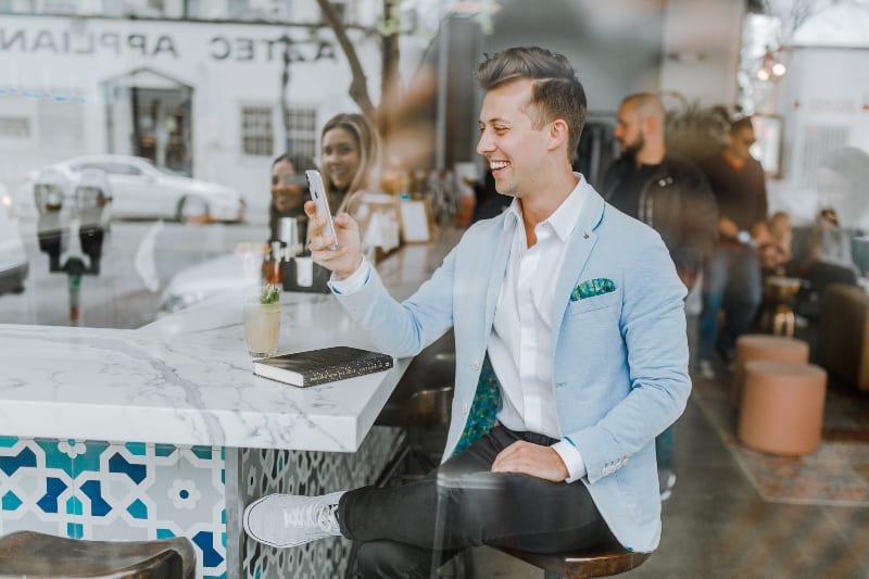 lächelnder Mann beim Halten des Smartphones