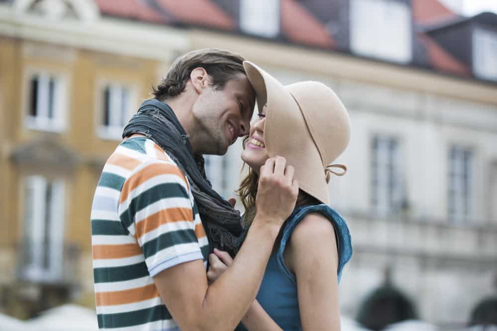 Ein Mann möchte eine Frau mit einem Hut küssen