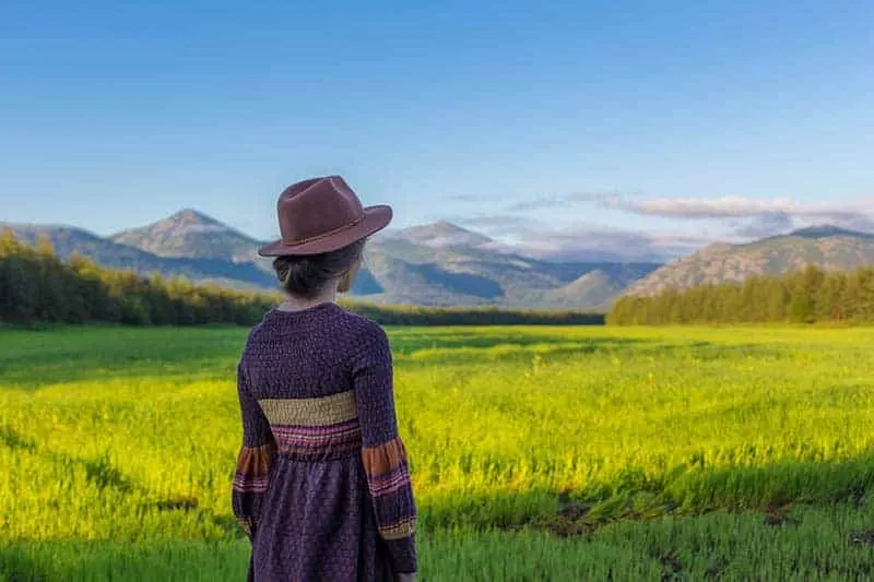 Eine Frau mit einem Hut auf dem Kopf steht auf einem Feld