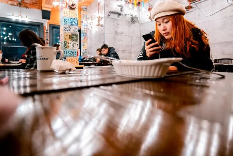 Eine traurige Frau in einem Restaurant benutzt ein Smartphone