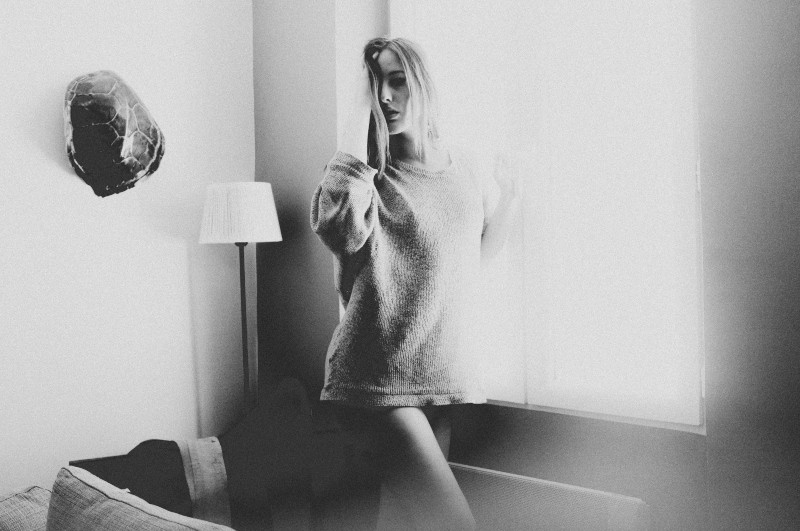 Frau im weißen Pullover sitzt auf Stuhl