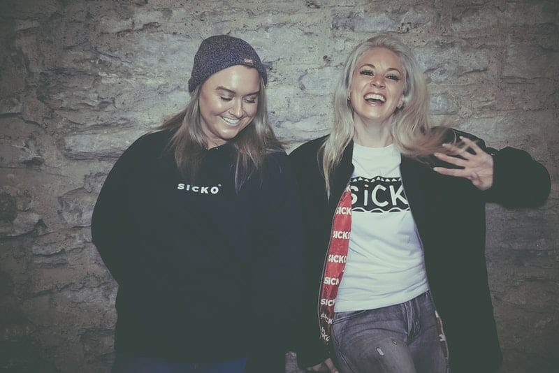 Zwei fröhliche Frauen stehen an der Wand