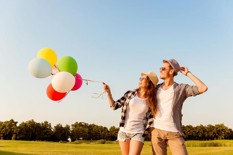 glückliches Paar, das mit Luftballons geht