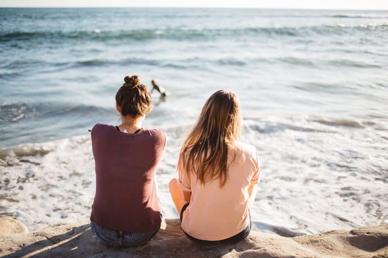 zwei junge Mädchen sitzen am Meer