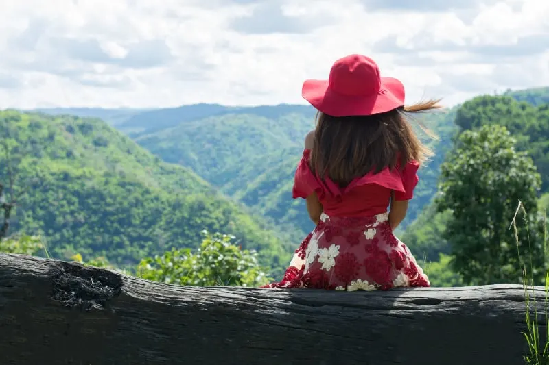 Das Mädchen sitzt allein in einem Kleid auf dem Berg