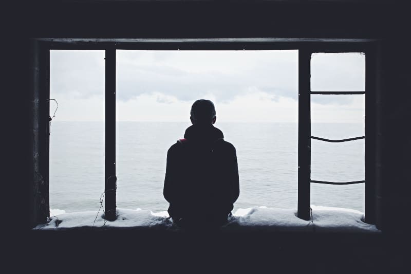 Ein einsamer junger Mann sitzt am Fenster