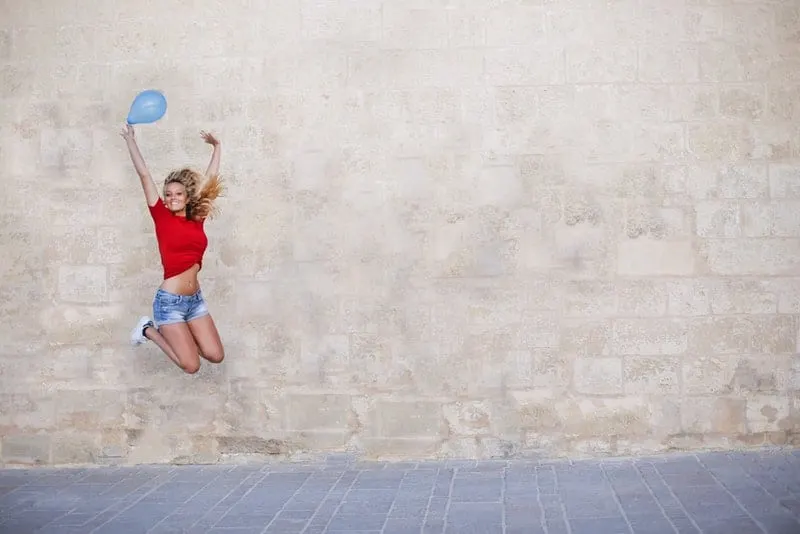 Eine Frau in kurzen Hosen mit einem Ballon in einem Fluss springt