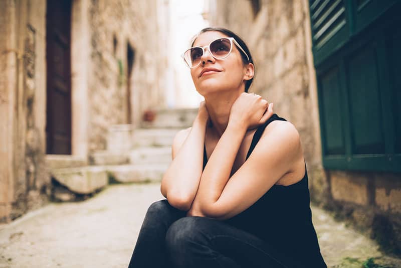 achtsame Frau mit Sonnenbrille, die draußen sitzt