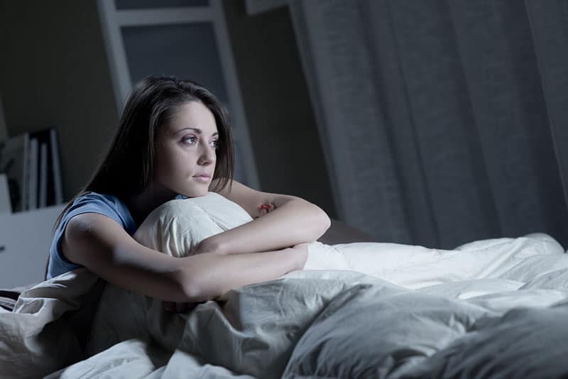 schläfrige Frau sitzt im Bett